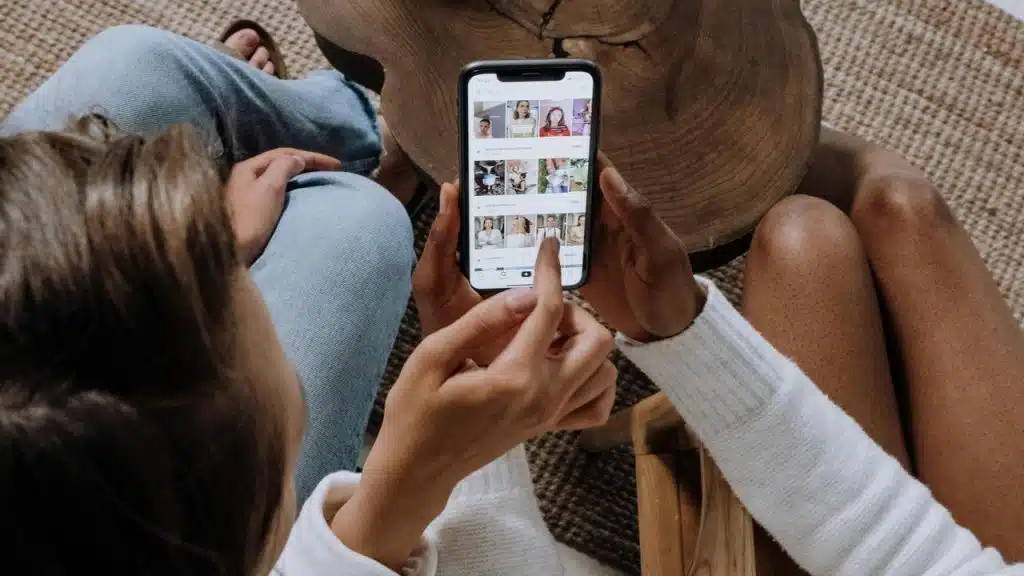 A person showing photos on a smartphone to someone sitting beside them.