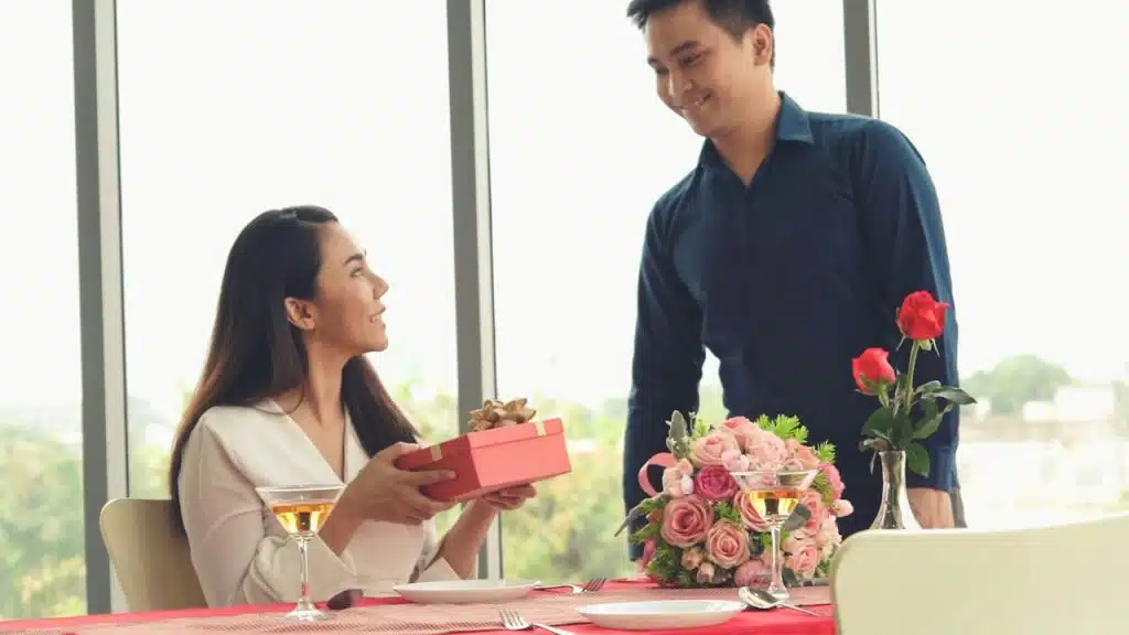 A man giving his girlfriend a present on a date.