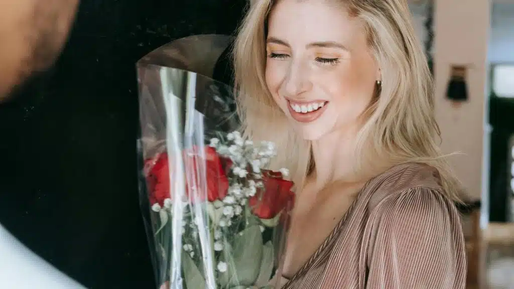 A smiling woman holding a bouquet of red roses