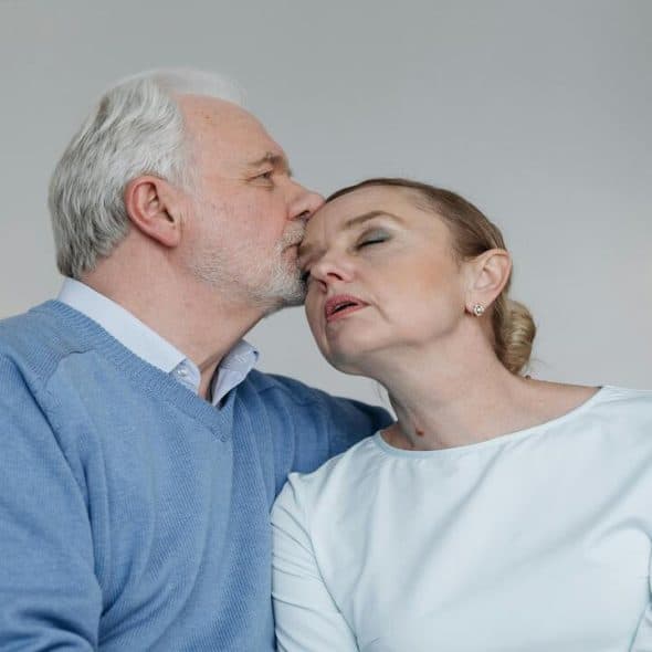 A man kissing his wife on the forehead