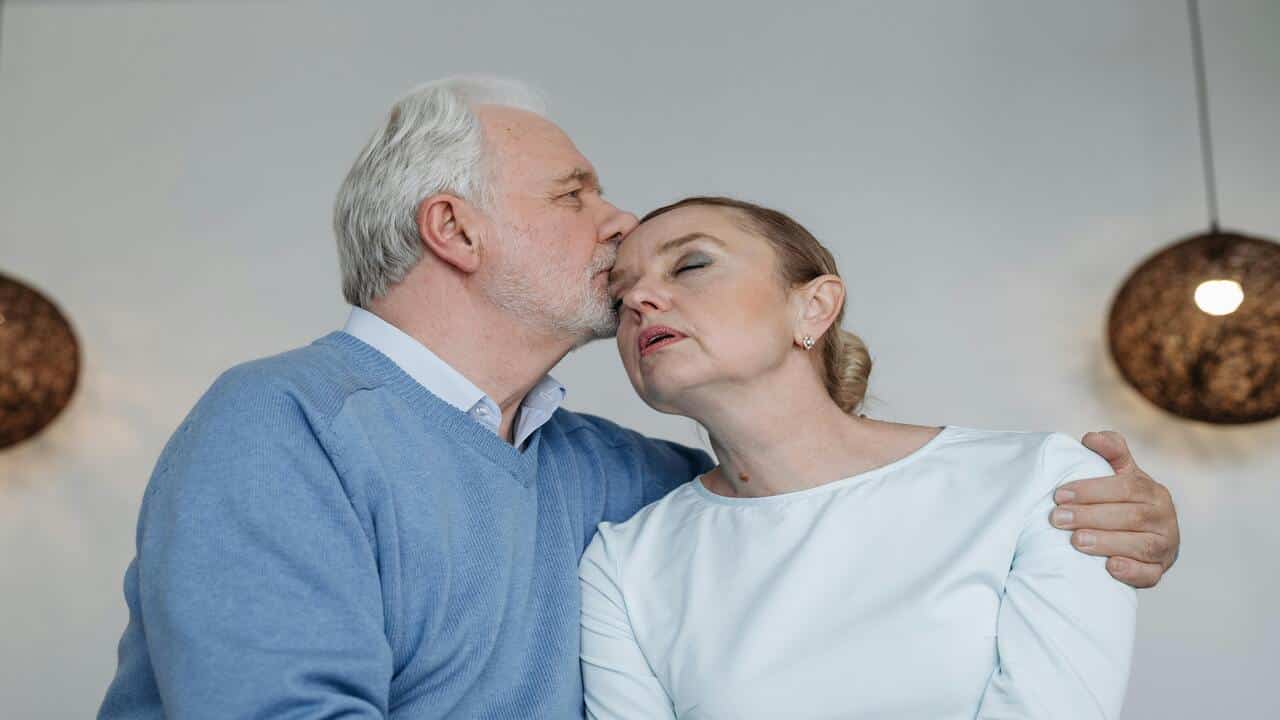 A man kissing his wife on the forehead 