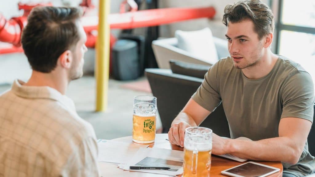 A pair of men talking over drinks