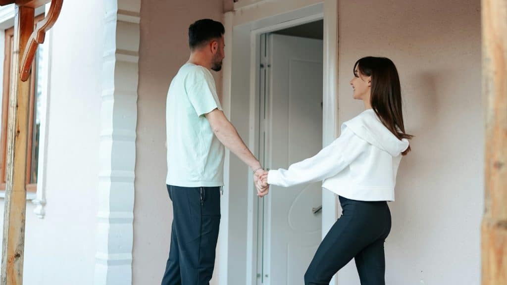 A man and a woman hold hands while standing in a doorway.