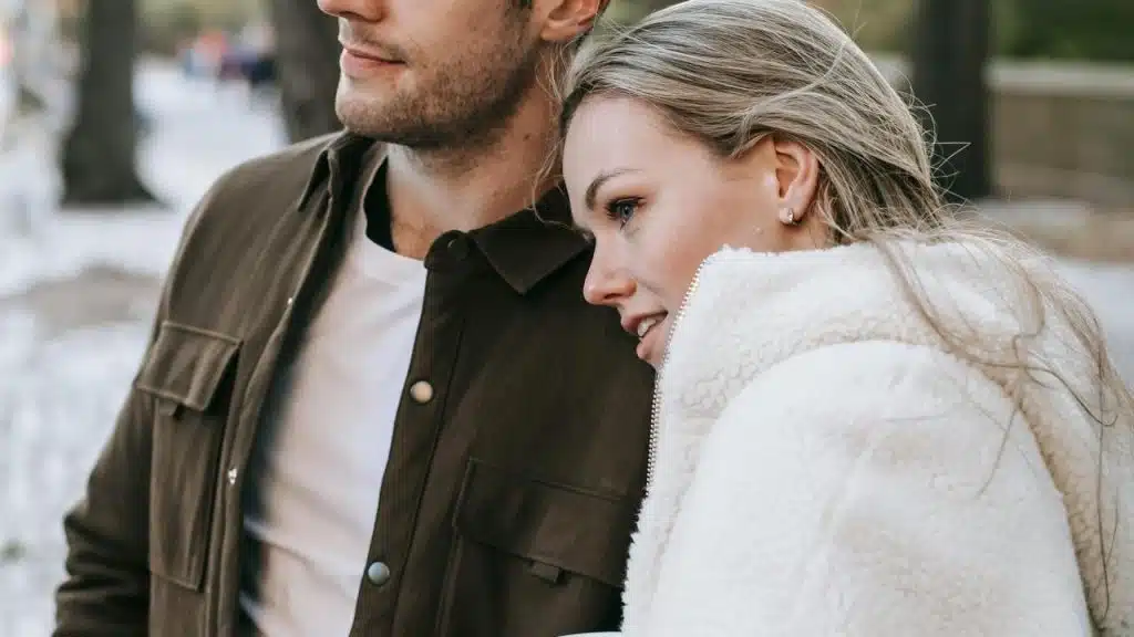 A woman leaning on a man while standing outdoors.