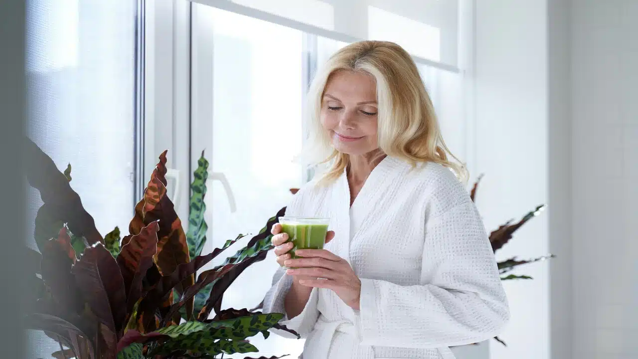 A beautiful mature woman drinking green juice