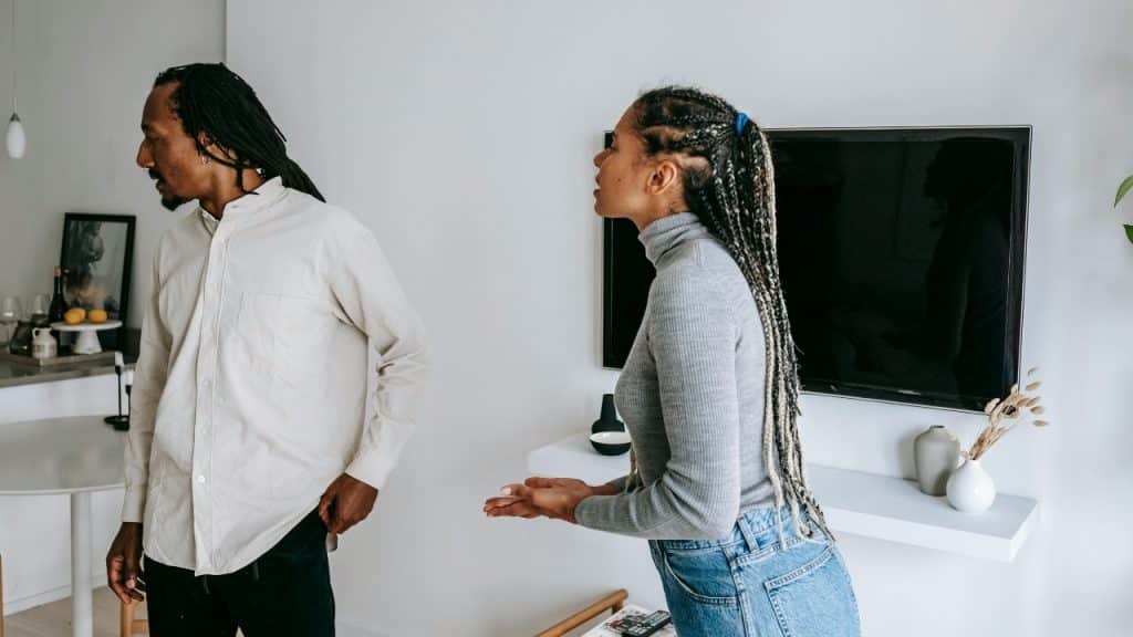 A woman gestures while talking to a man standing with his back to her.