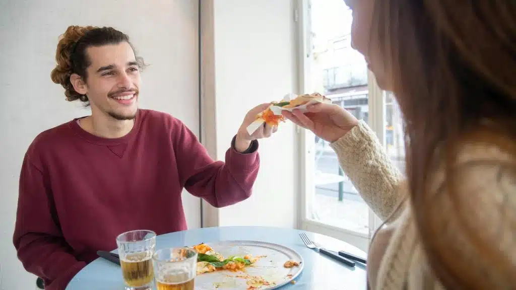 A smiling man reaches across a table