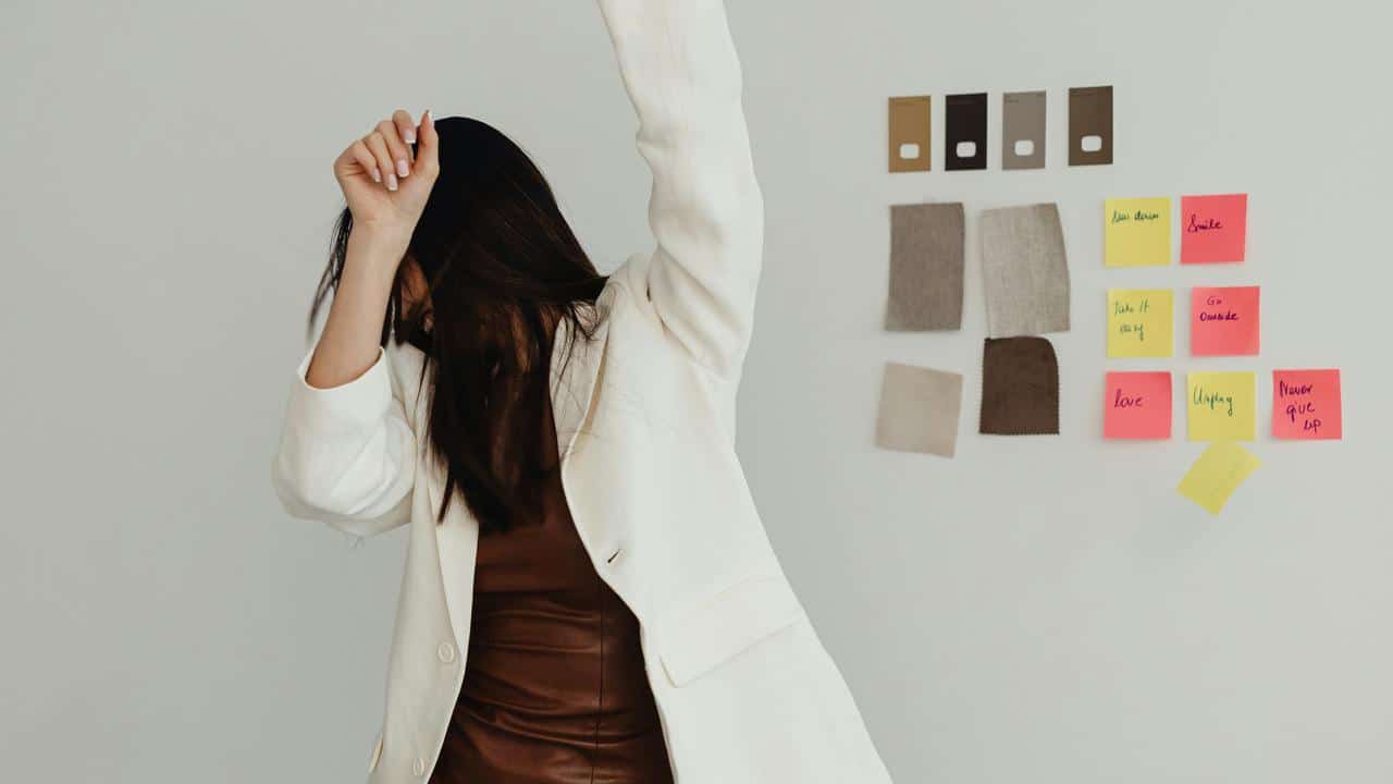 A woman dancing joyfully indoors with one arm raised.