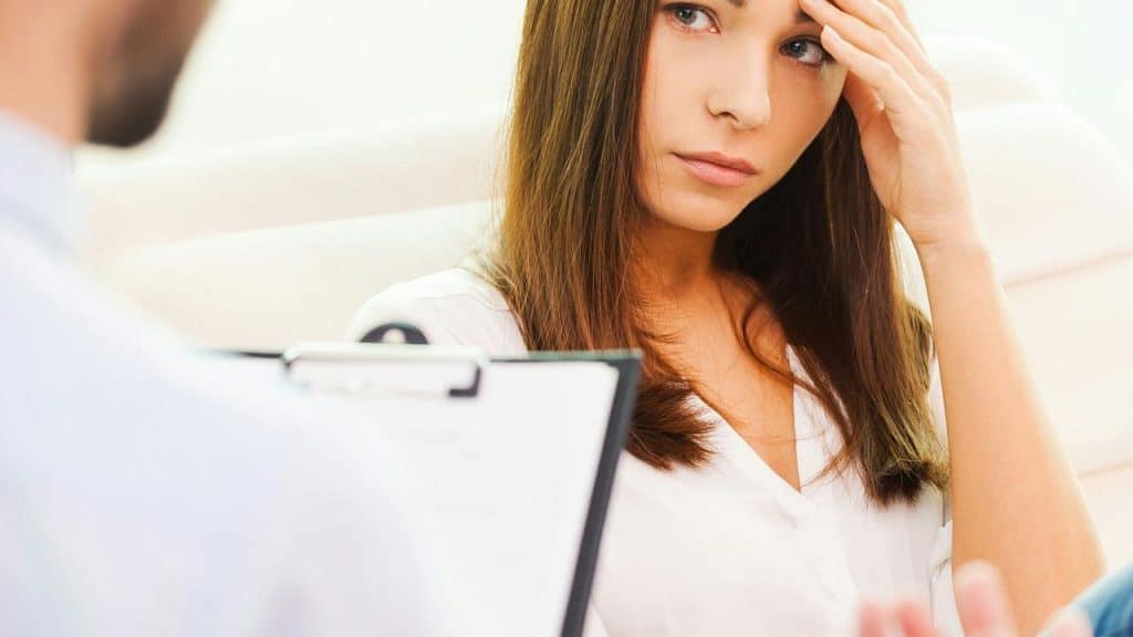 A woman touching her forehead while listening intently