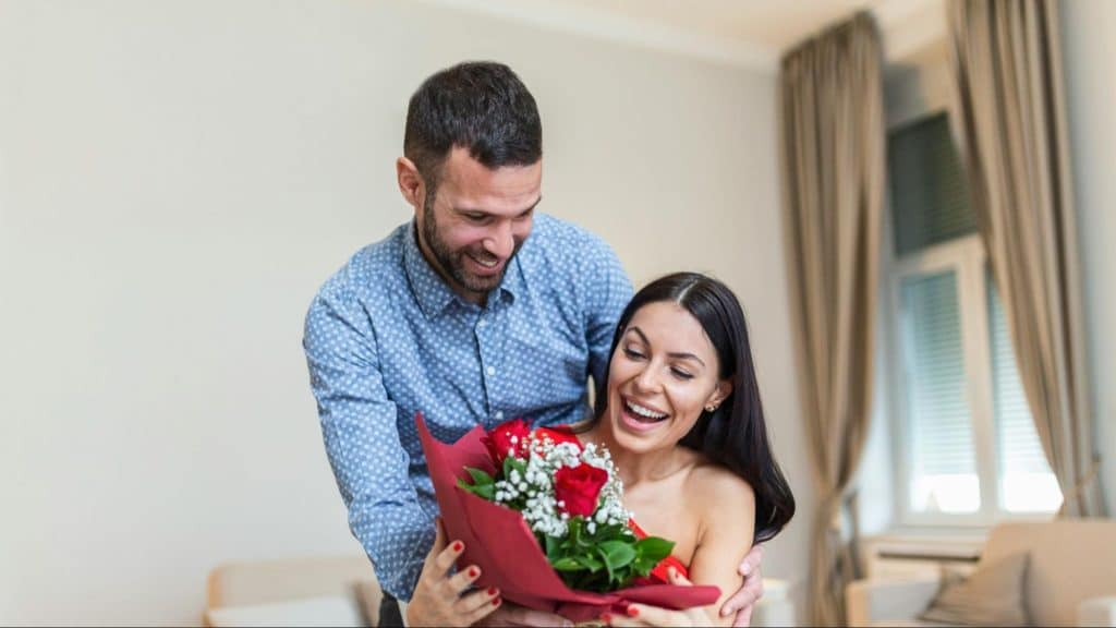A man holding a flower to give to woman