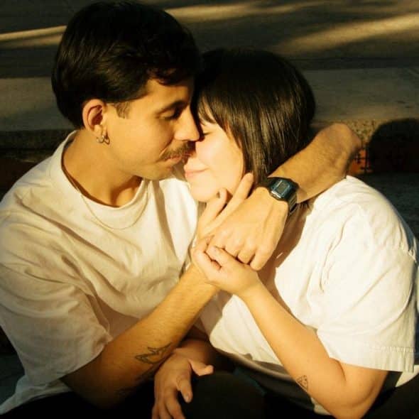 A man and a woman hugging each other while they are sitting on the stairs.