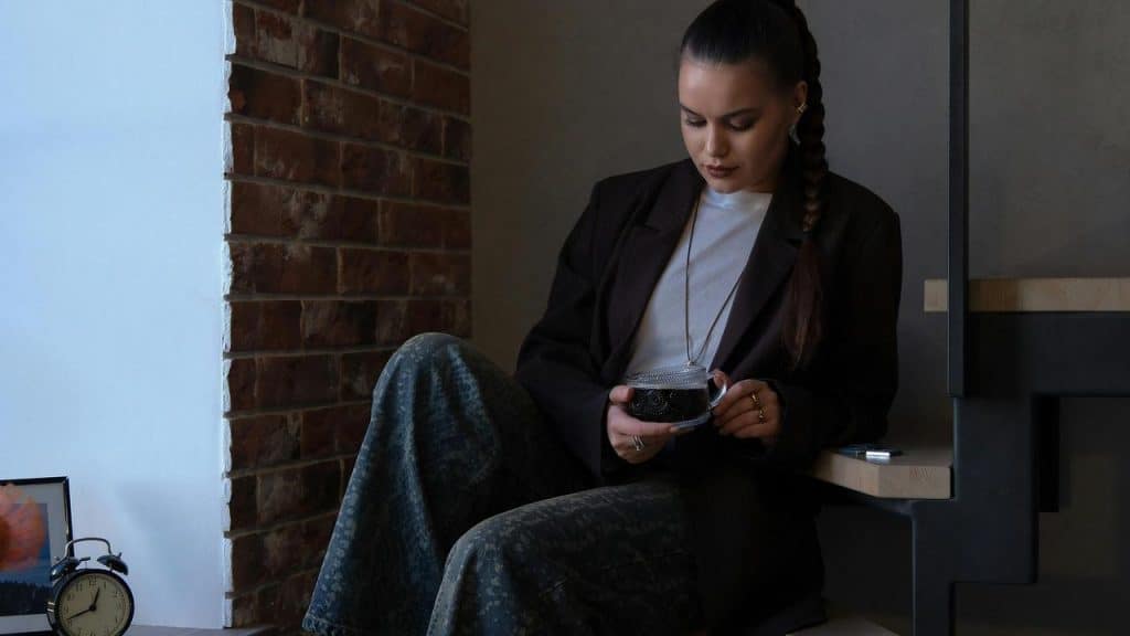 A woman sitting by a window holding a cup