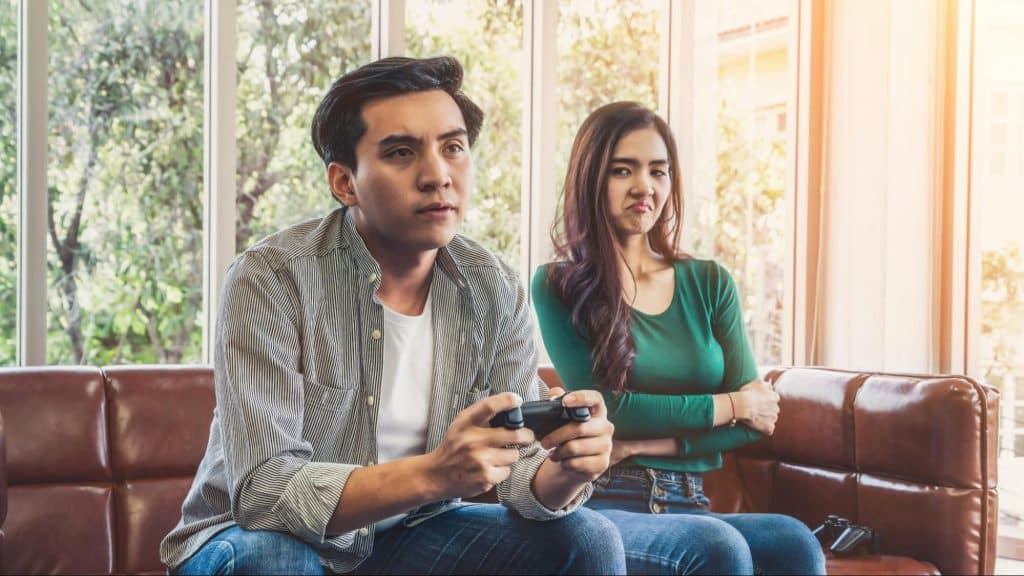 A man playing games and a woman, annoyed with it 
