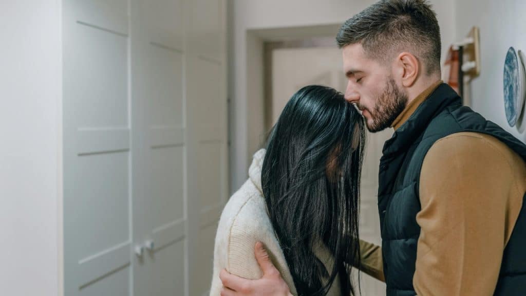 A man with a beard leans his forehead against a woman with long dark hair.