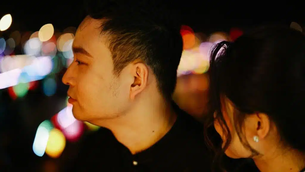 A man looking to the side as a woman stares at him.