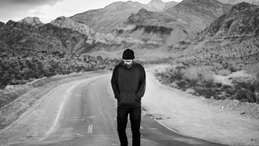 A man in a black jacket walking on a road.