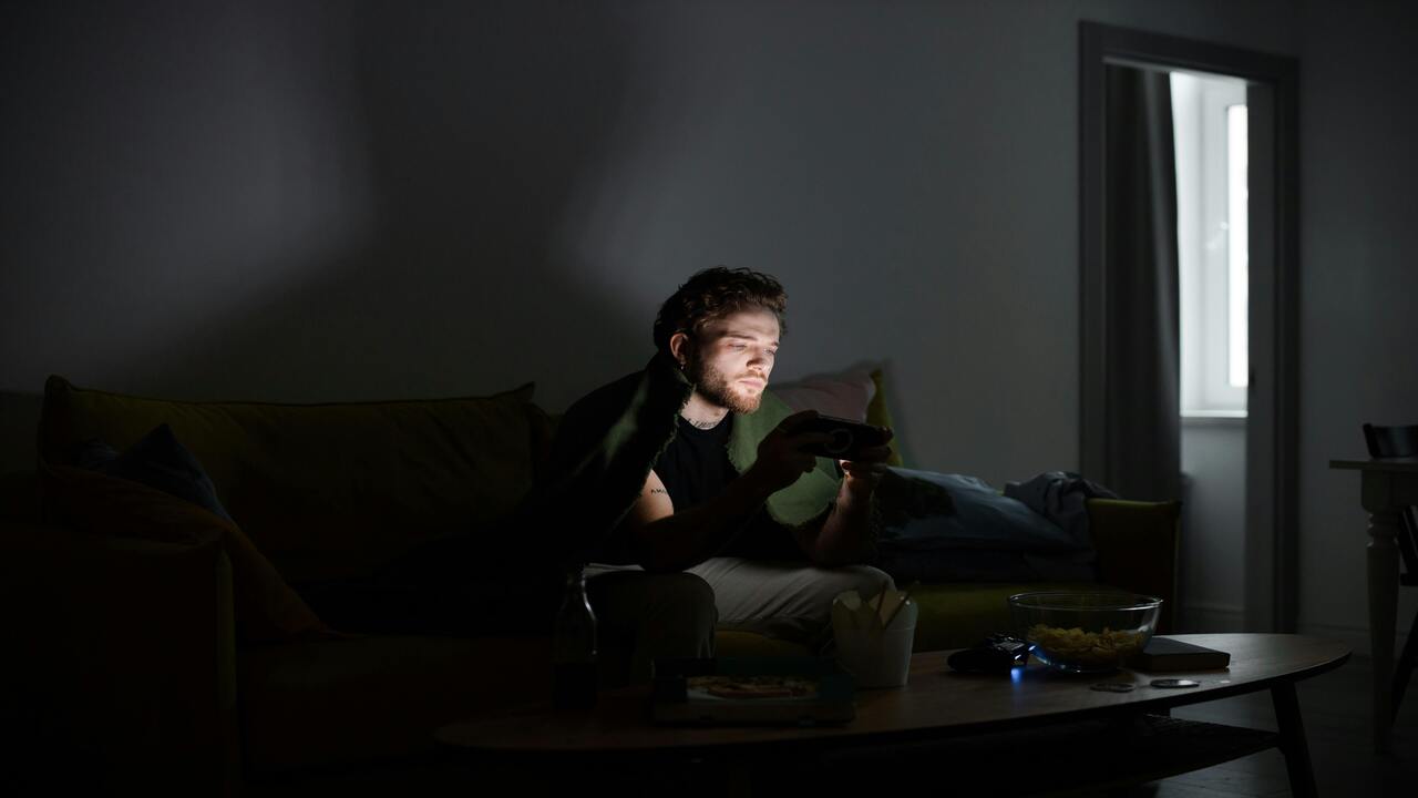 A man playing phone games in the dark