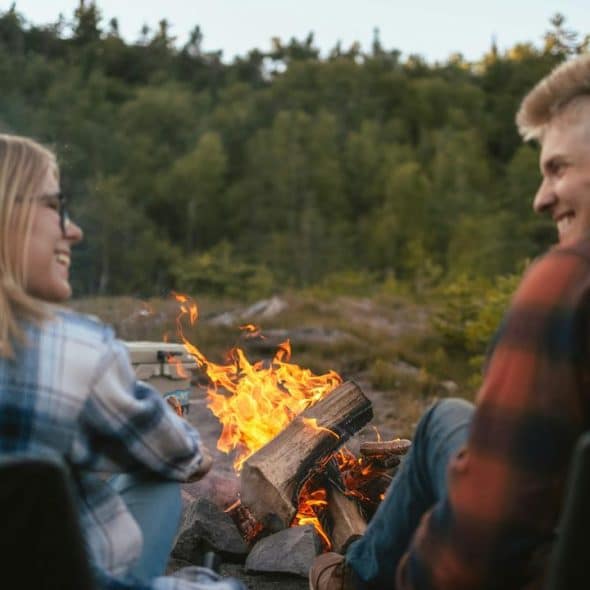 A couple sitting by a campfire outdoors
