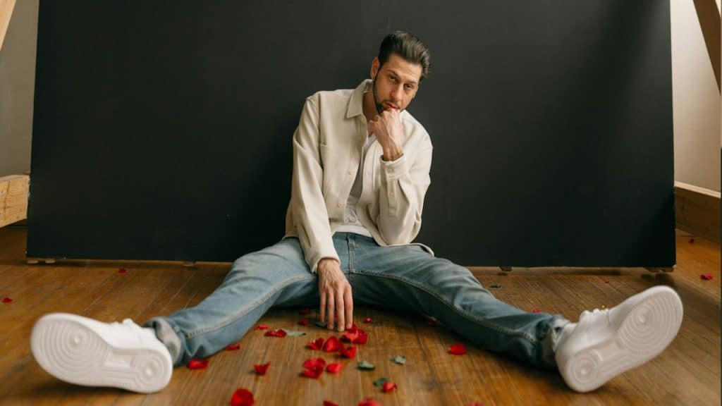 A man sitting on the floor with petals of roses.