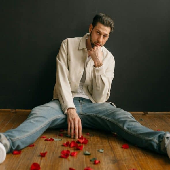 A man sitting on the floor with petals of roses.