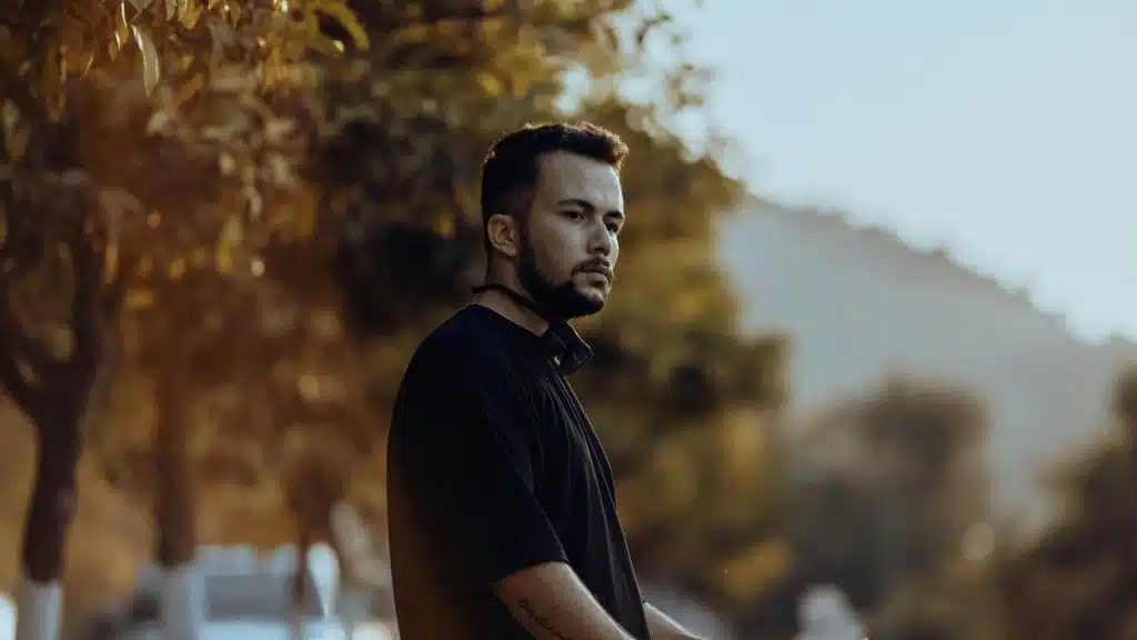 A man standing outdoors near trees, looking off into the distance