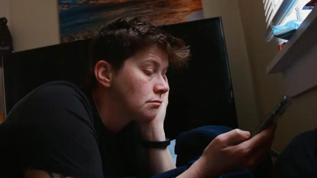 A person lying down while looking at a phone.