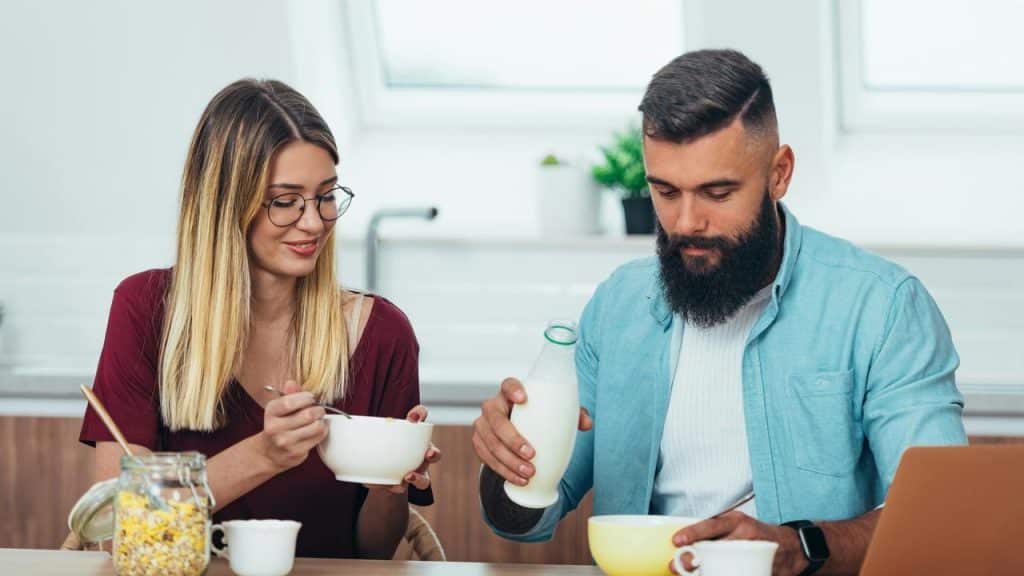 A couple having breakfast together at a kitchen table.