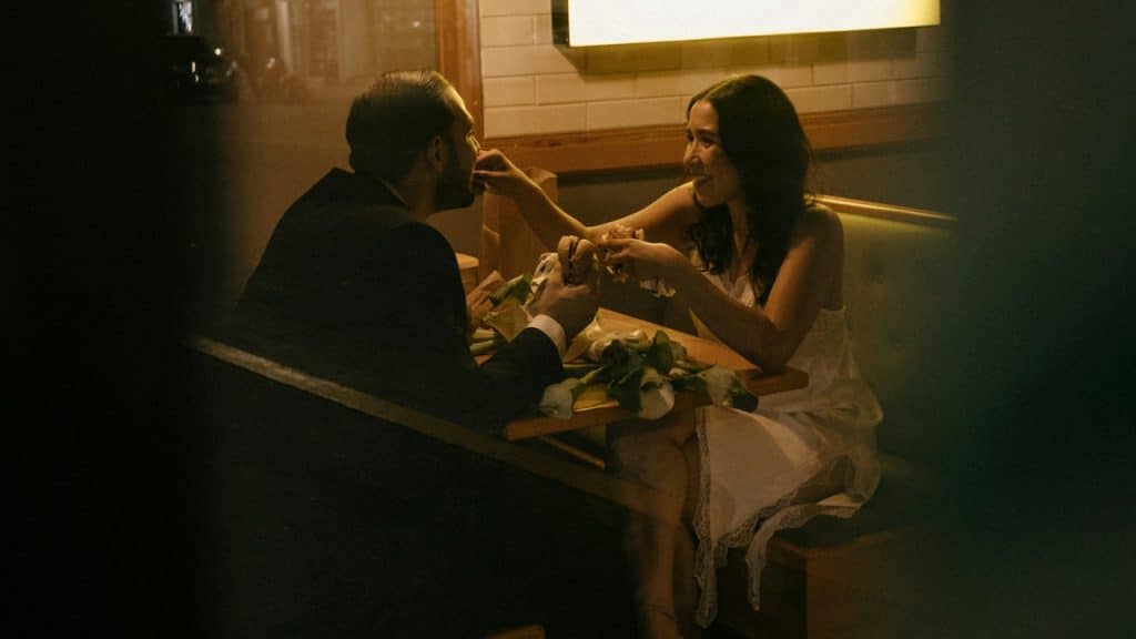 A couple eating at a booth in a dimly lit restaurant.
