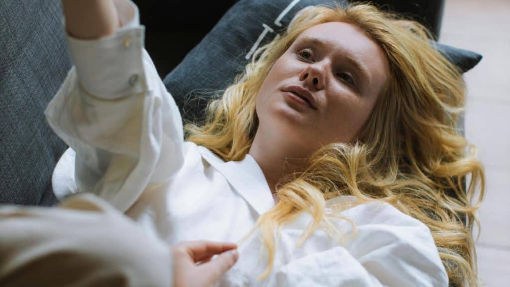 A woman lying on a couch looking up thoughtfully.
