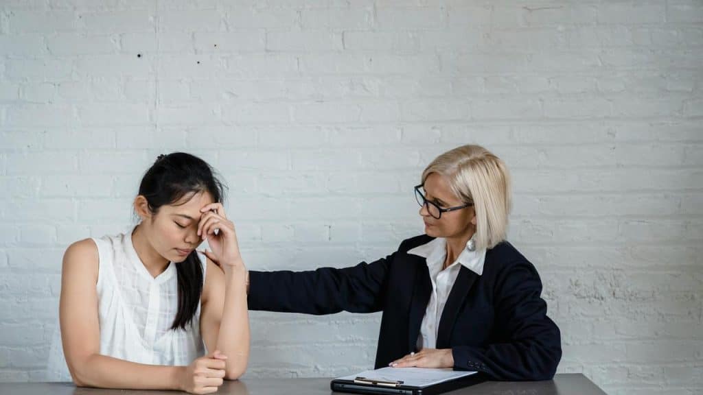 A counselor comforting a distressed woman at a table.