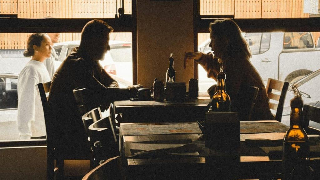 A backlit café scene with two people talking across a table