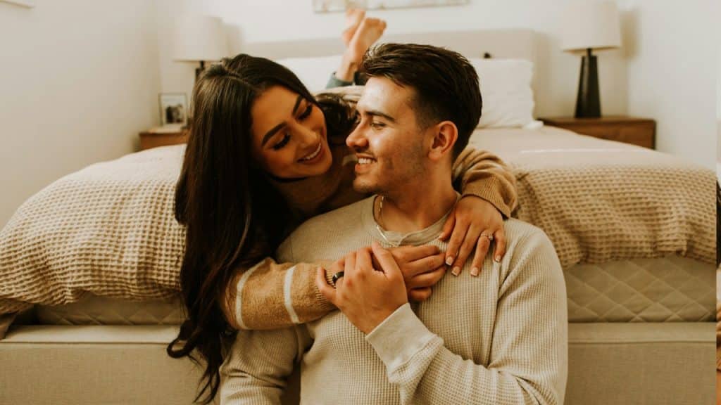 A man and a woman sitting on a bed together.