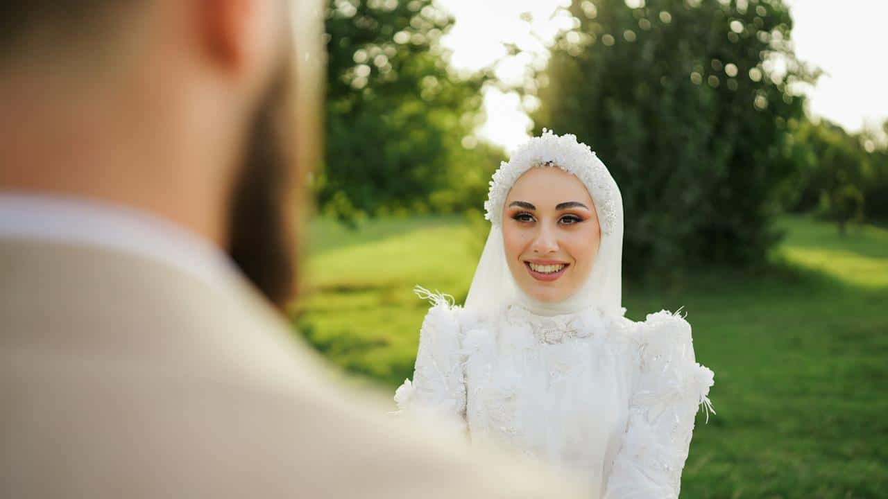 A woman in a white dress is standing in front of a man.