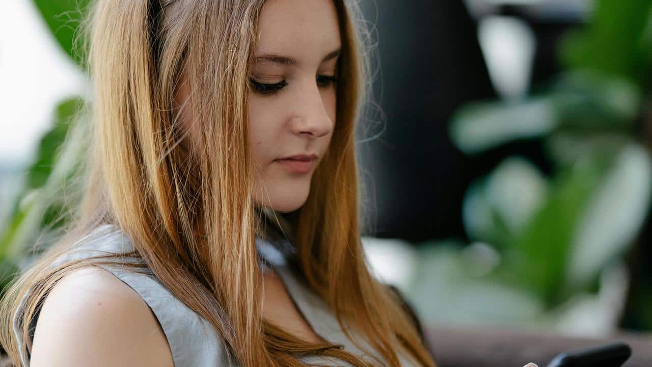 A young blonde woman looking down at her phone