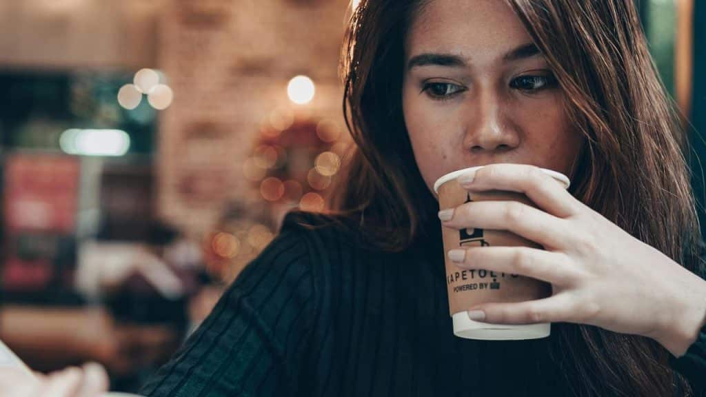 A woman drinking from a takeaway coffee cup