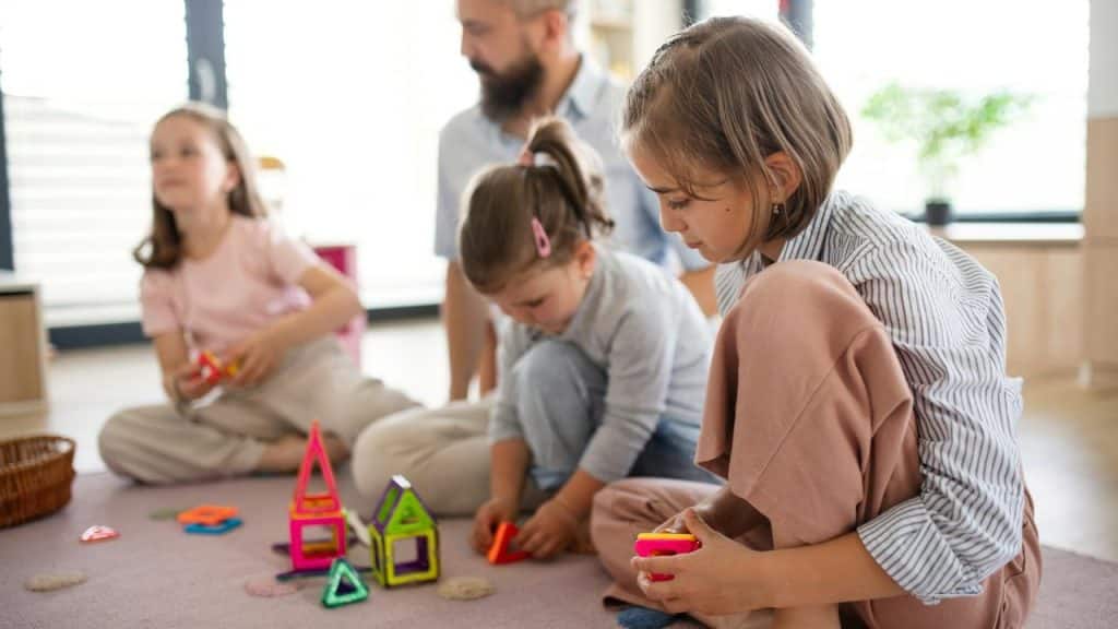 A family sitting on the floor building with colorful toy blocks.