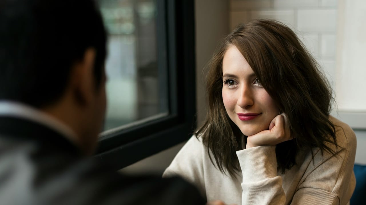A woman looking at her partner while sitting at a table together.