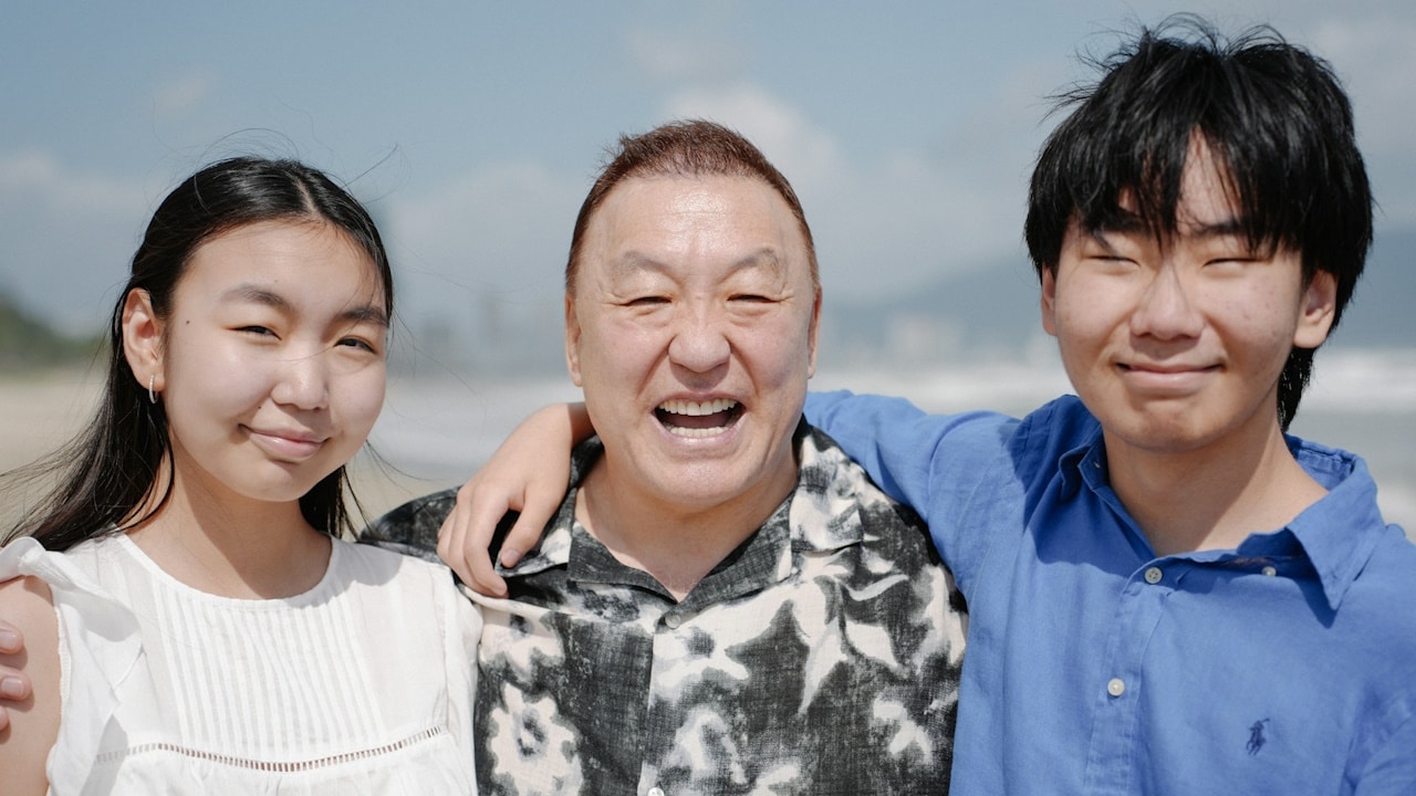 A man and two children on a beach.