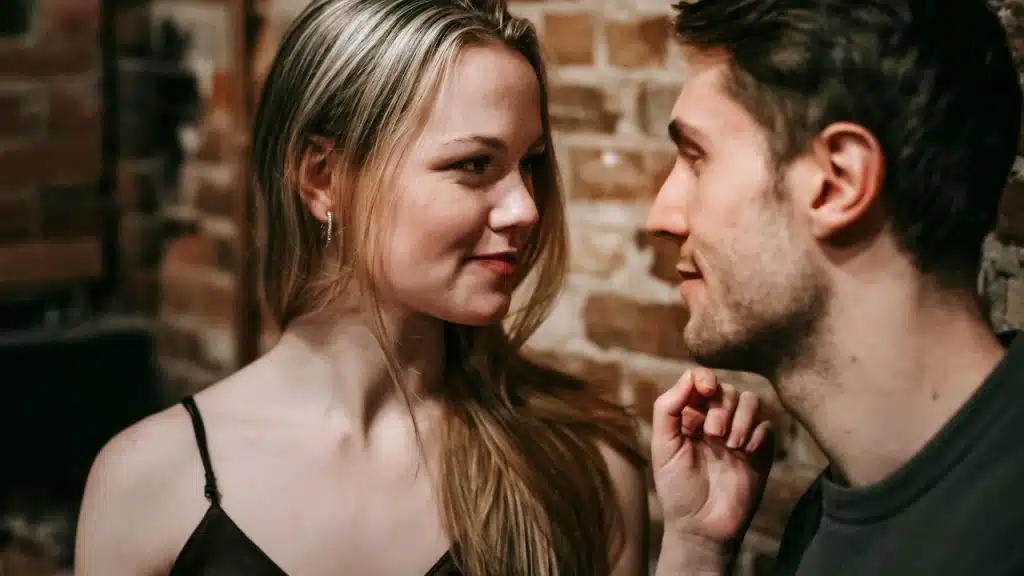 A woman looks at a man while he touches his chin near his mouth.