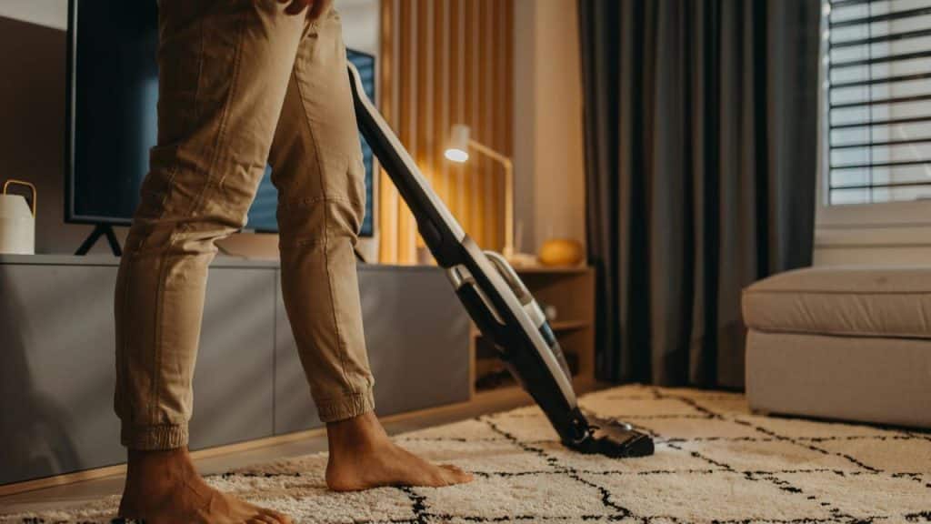 A person vacuuming a carpet in a living room.
