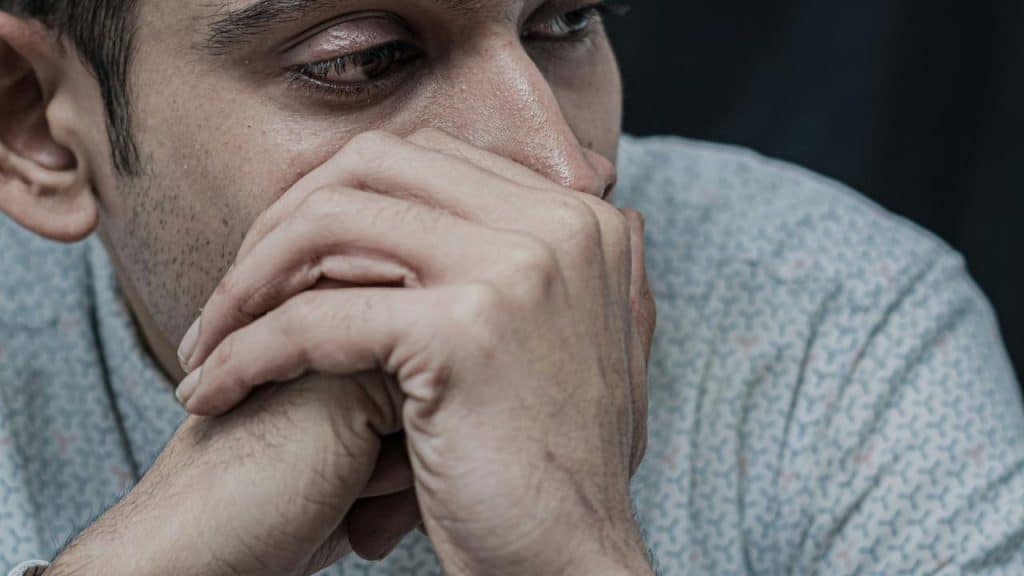 A person covering their mouth, looking concerned