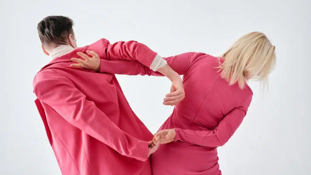 A man and a woman in pink clothes are facing each other.