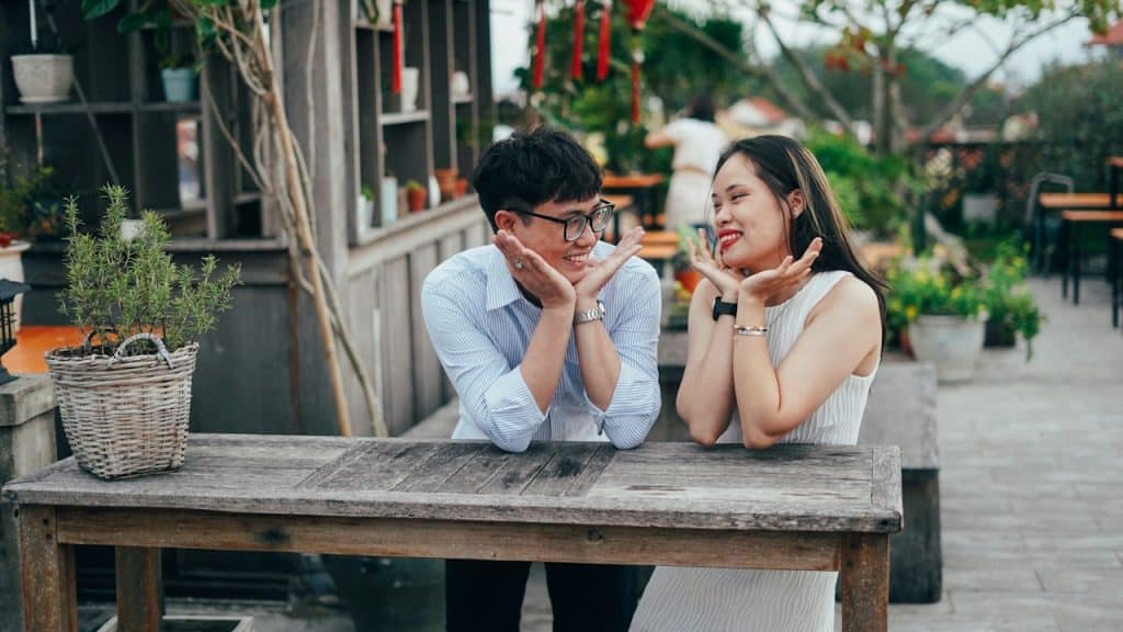 A man and a woman sitting at a wooden table.