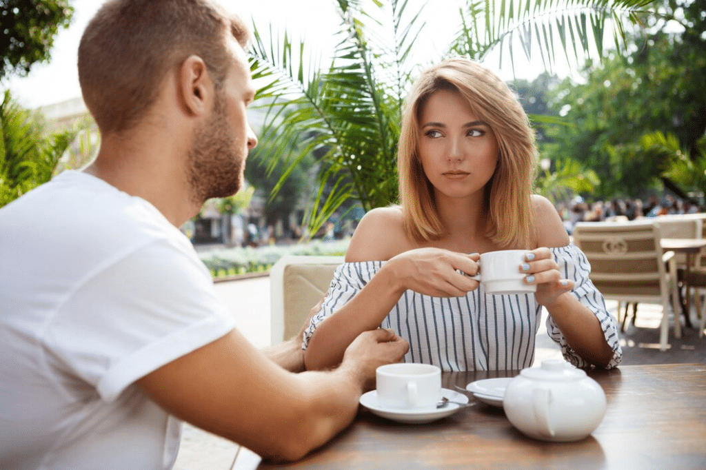 Young beautiful couple quarreling, sitting in cafe