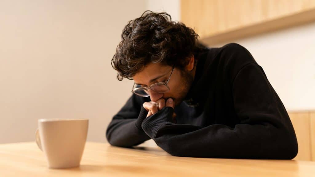 A man sitting at a table with a coffee cup in front of him.