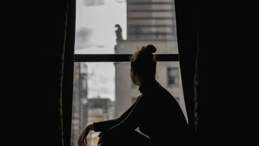 A person sitting in silhouette by a window