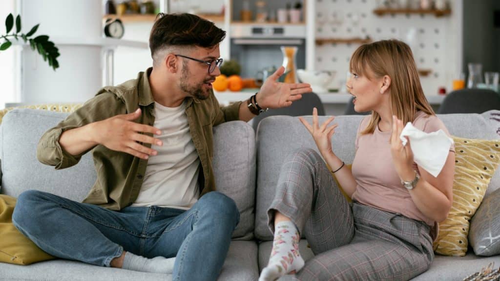 A man and a woman arguing while sitting on a sofa.