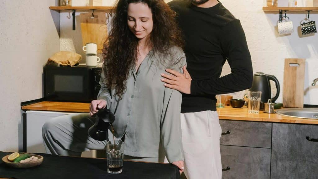 A couple making coffee together in a kitchen.