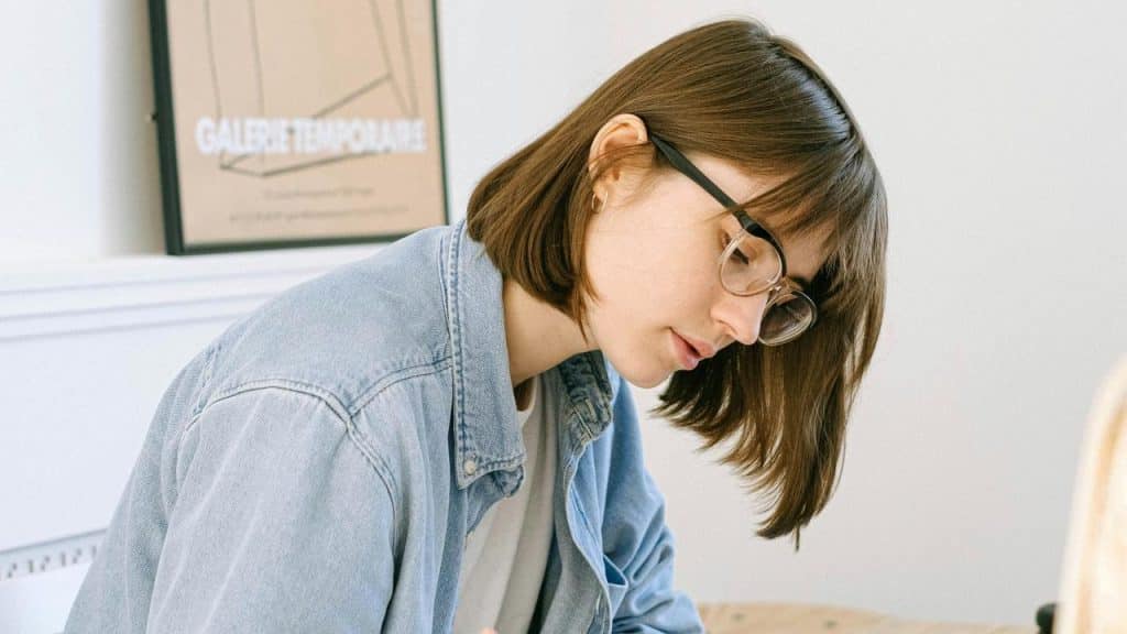 A woman with glasses concentrating while working at a desk.