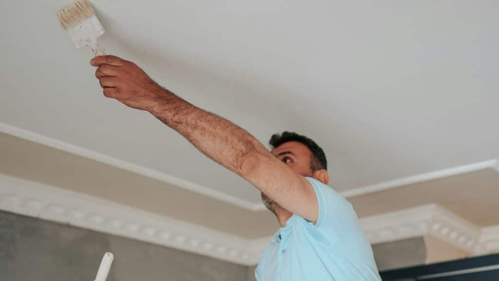 A man painting a ceiling.